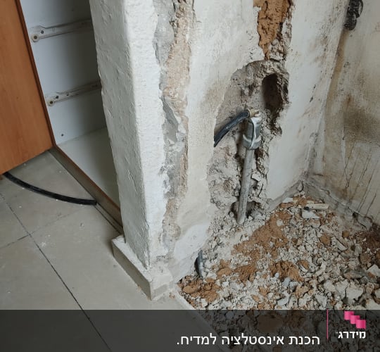 קיר שבור עם צינור מים חשוף ותשתית בנייה